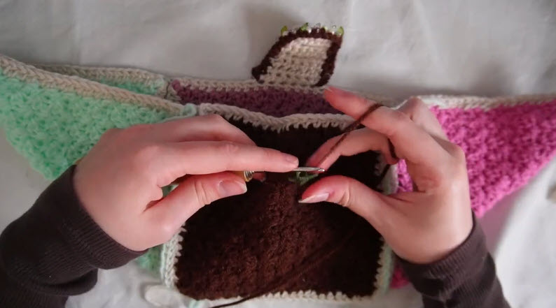 Crocheting brown edge on colorful patchwork blanket