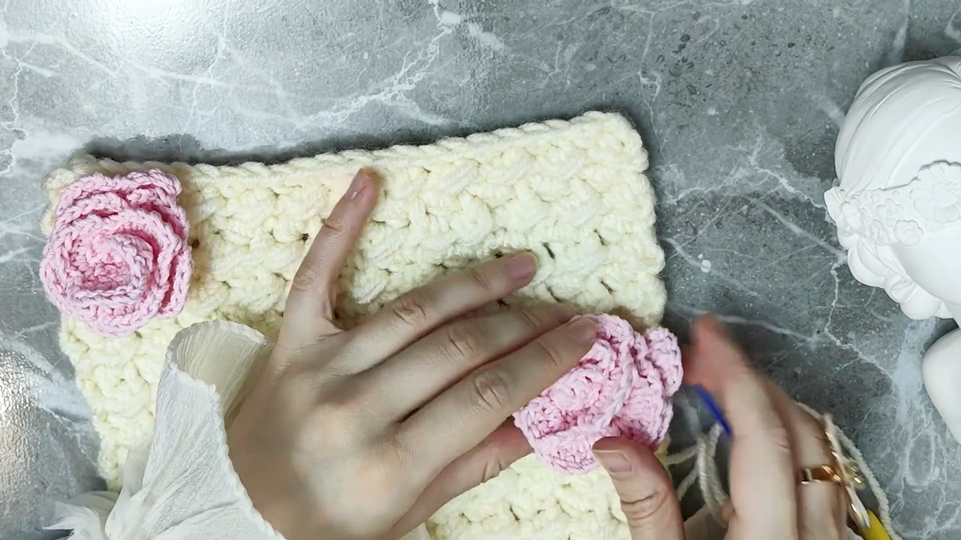 Attaching pink crochet roses onto finished cream scarf