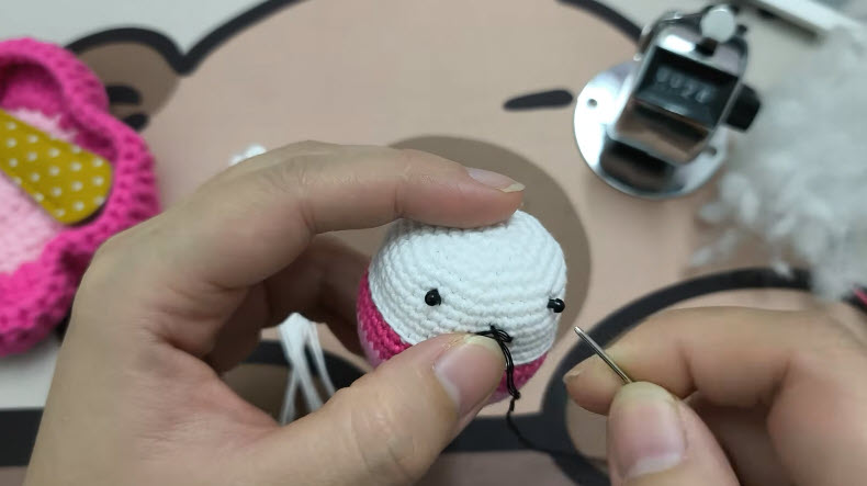Bead eyes and stitched mouth on a chubby crochet bunny keychain