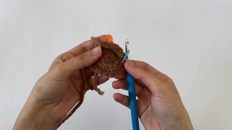 Brown crochet ear shape R4 FLO stitches being made, orange marker visible.