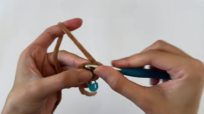 Brown piece R2 increase round, stitch marker attached as the hook works.