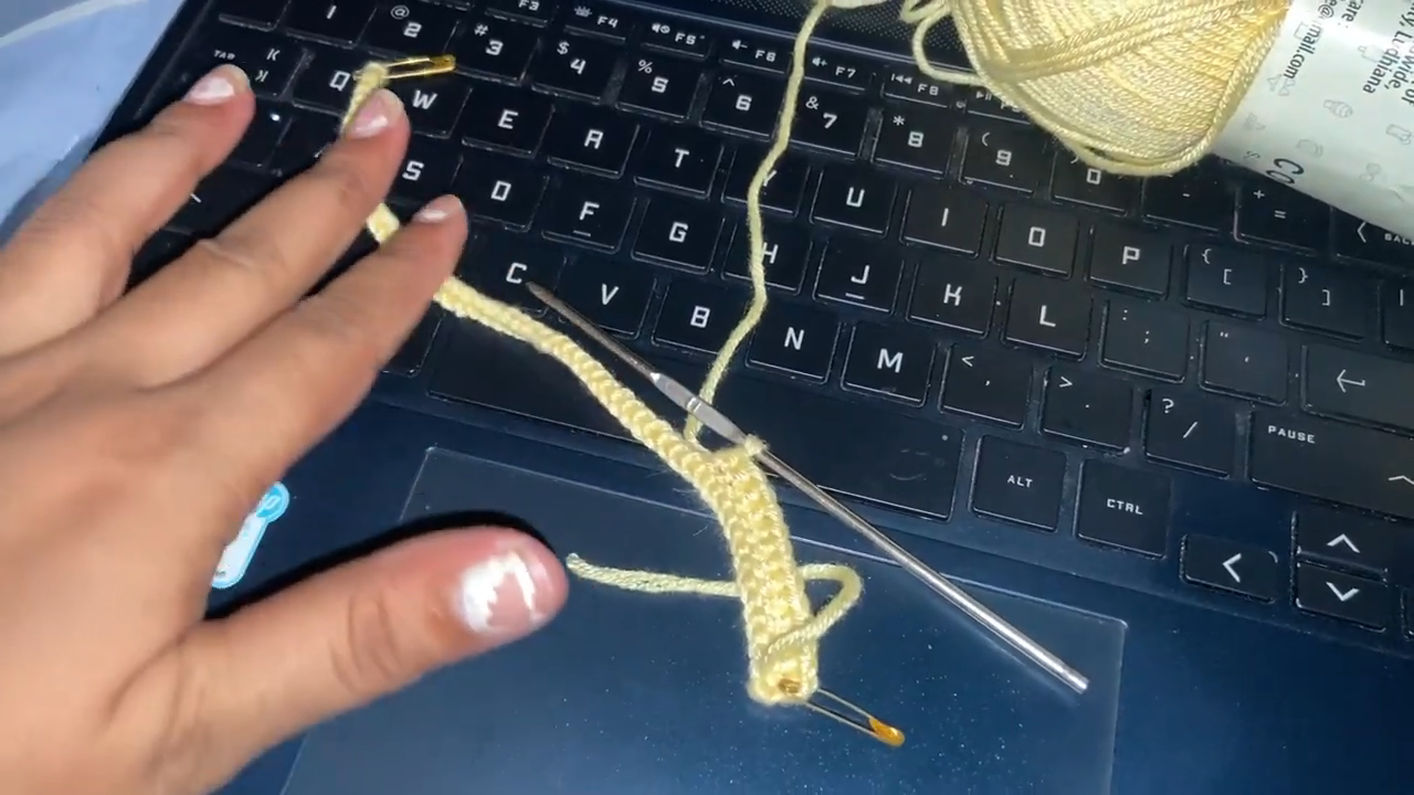 Crocheting yellow strap piece with steel hook