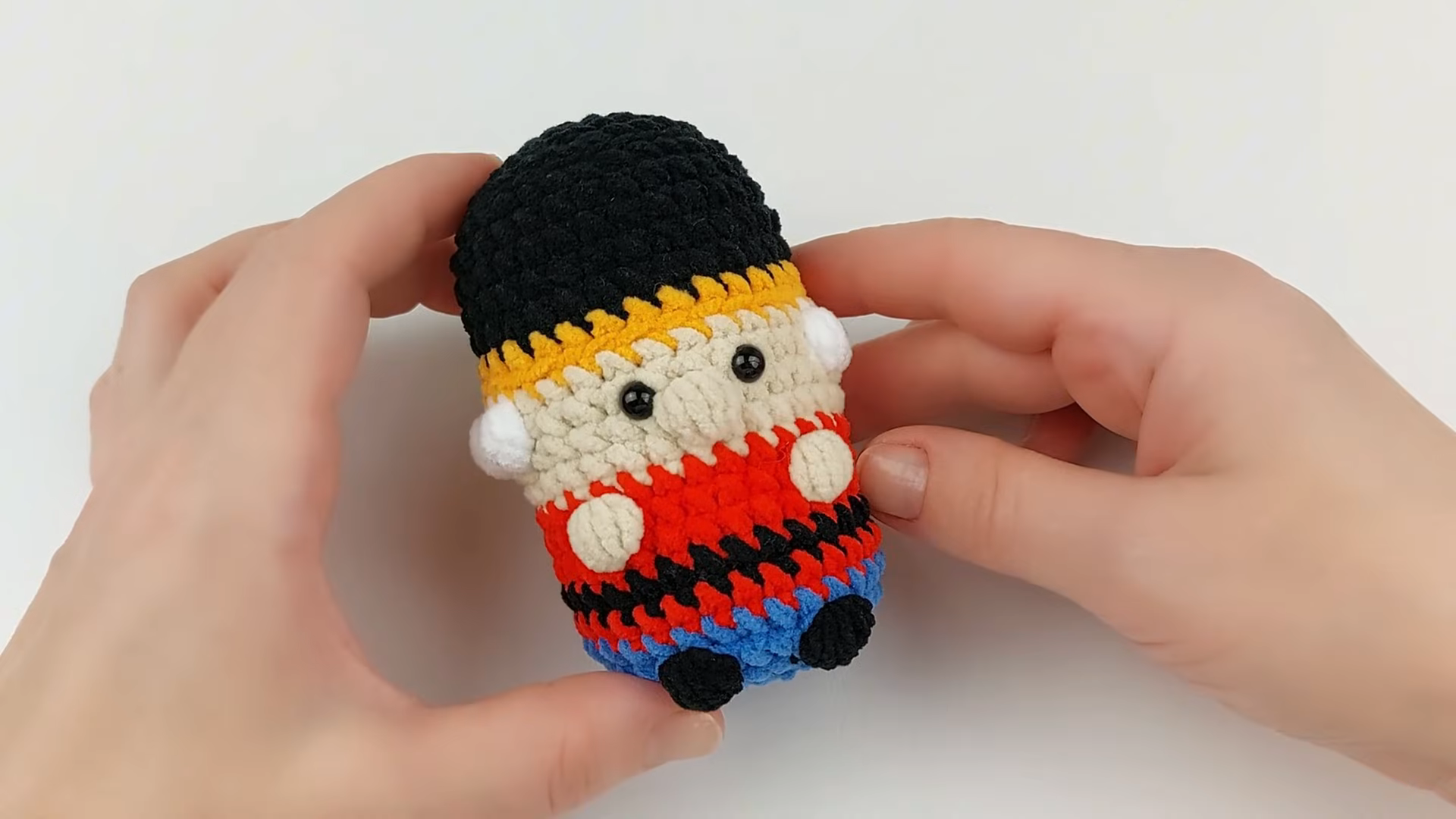 Finished nutcracker keychain with black hat, beige face, red and blue striped body.