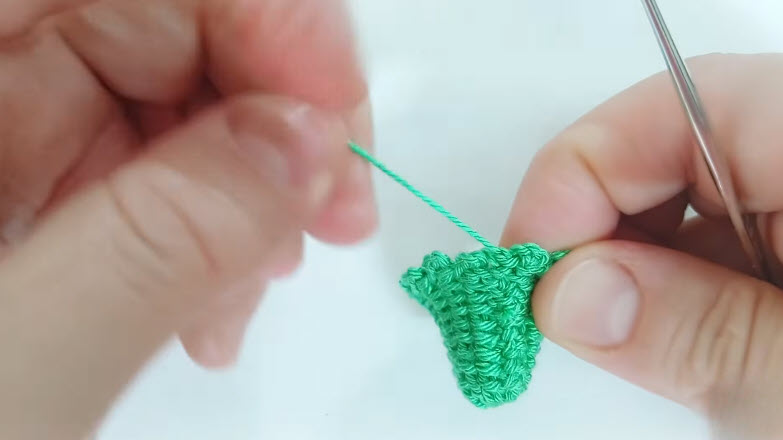 Finishing yarn tail on green crochet earring piece