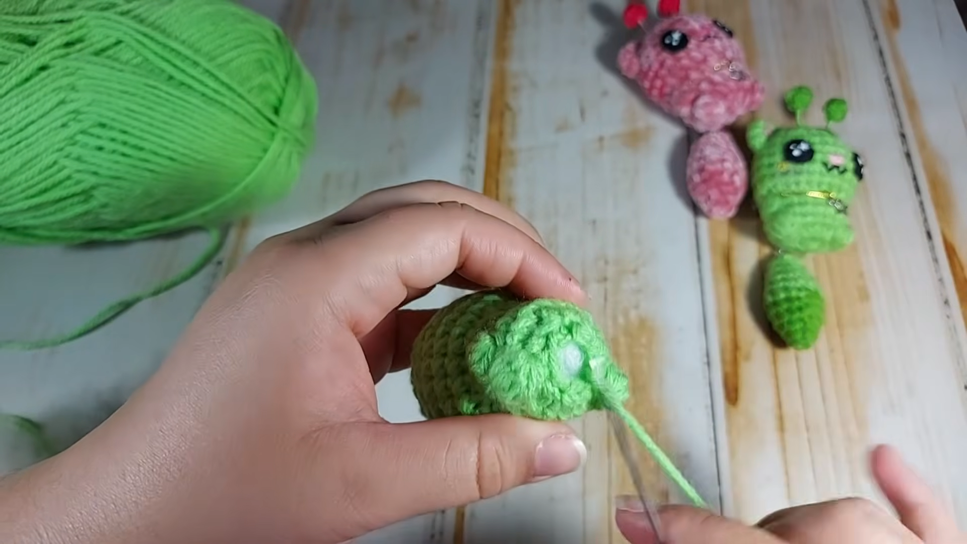 Inserting safety eye into green amigurumi head piece