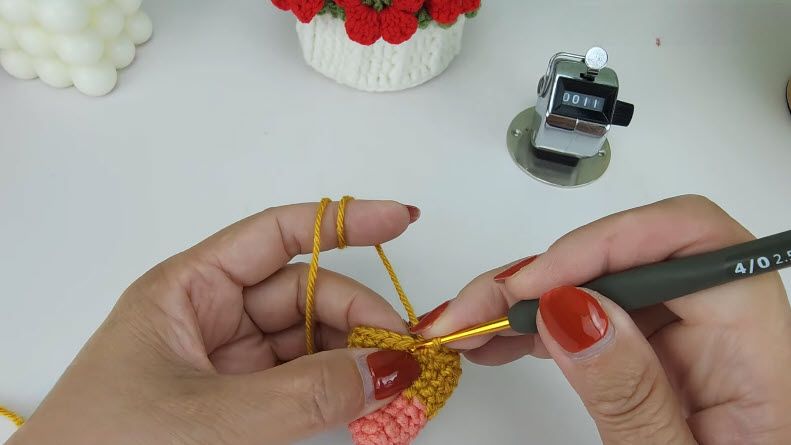 Mustard yellow crochet cone R11 round, hook working the stitches.