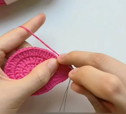Needle sewing through the pink crochet round base.