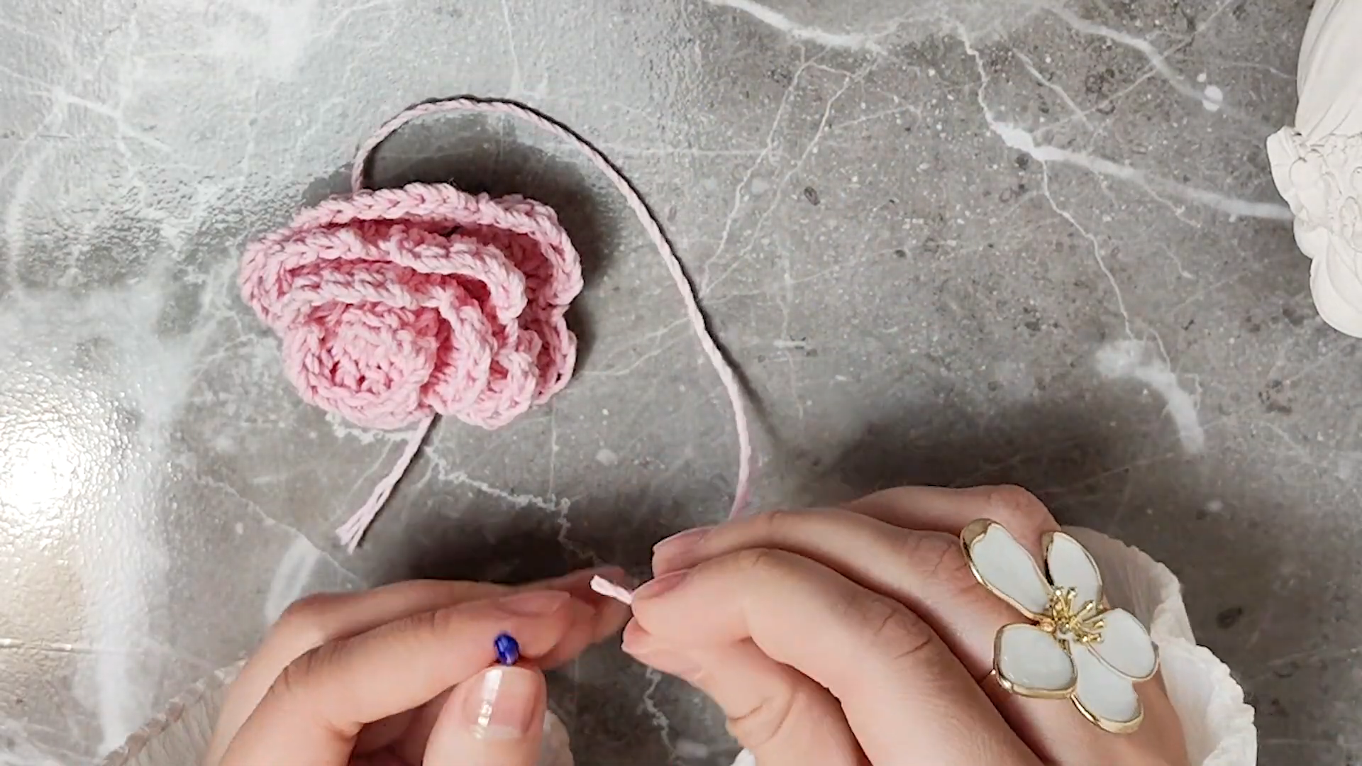 Pink crochet rose motif with yarn tail for attaching