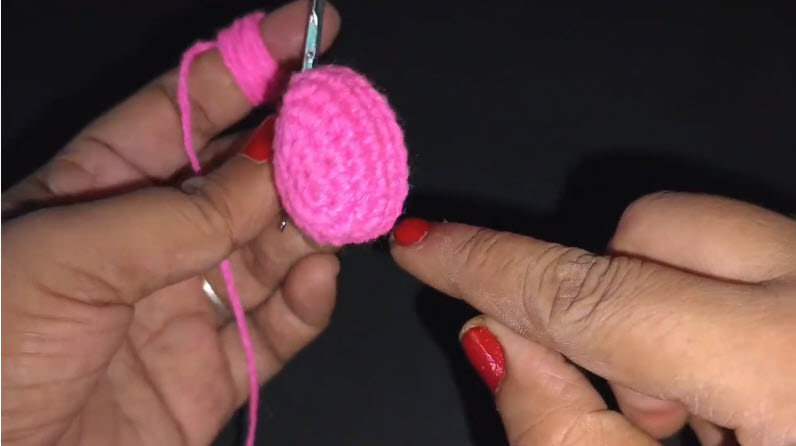 Pink crocheted egg shape held up for keychain