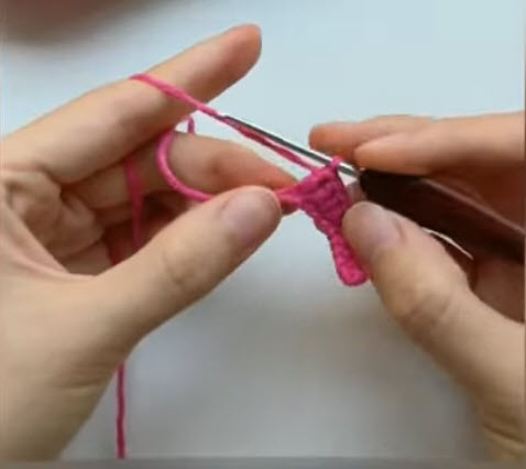Pink petal shape starting on the crochet hook.
