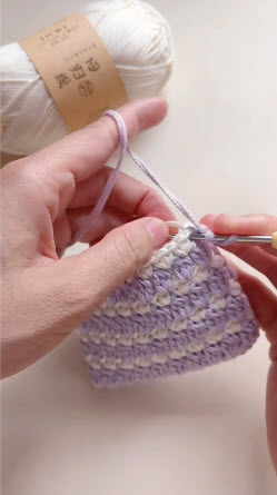 Purple and white bobble stitch pattern taking shape on holder