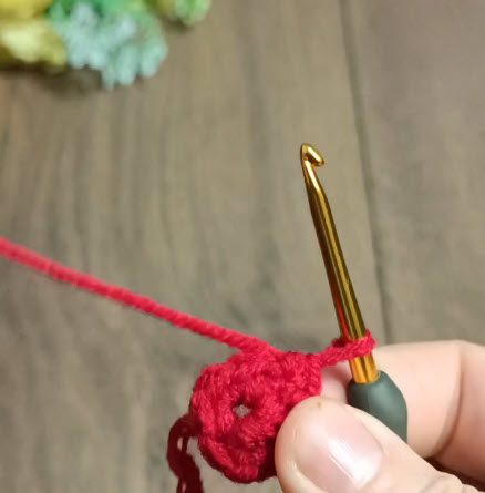 Red crochet round base starting to form on the hook.