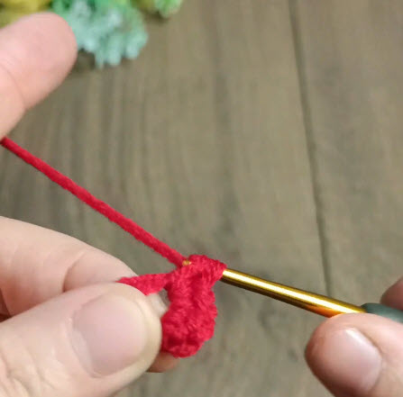 Red yarn loop being tightened around the crochet hook.