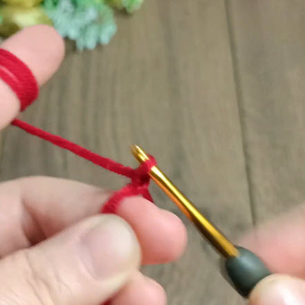Red yarn slip knot being made on the crochet hook.