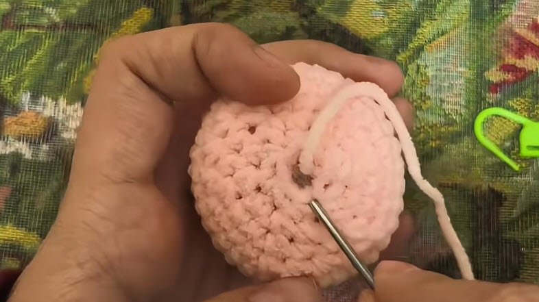 Peach crochet piece worked through the decrease rounds.