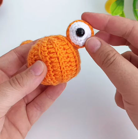 White felt eye with black safety eye attached to a crochet pumpkin