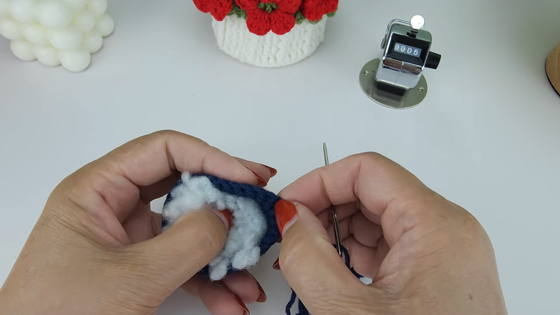 White stuffing being pushed into the navy crochet base.