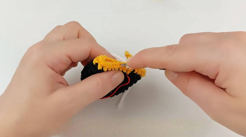 Yellow and black crochet piece R12 BLO round, red yarn tail visible.
