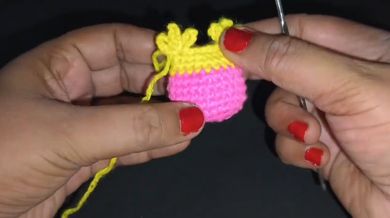 Yellow crocheted owl ears attached above pink body