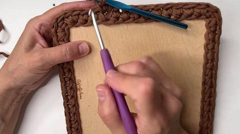 Braided brown stitch edge forming a border around the wood.
