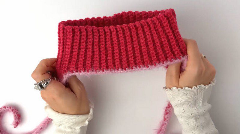 Completed red crochet cap band with a soft pink fuzzy edging.