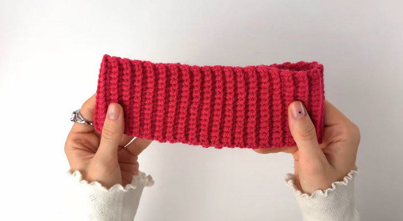 Finished ribbed red strip stretched between both hands.