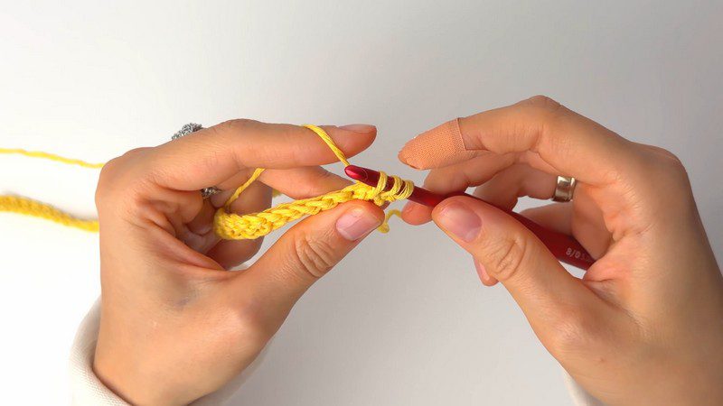 First ribbed row of yellow yarn wrapped around the hook.