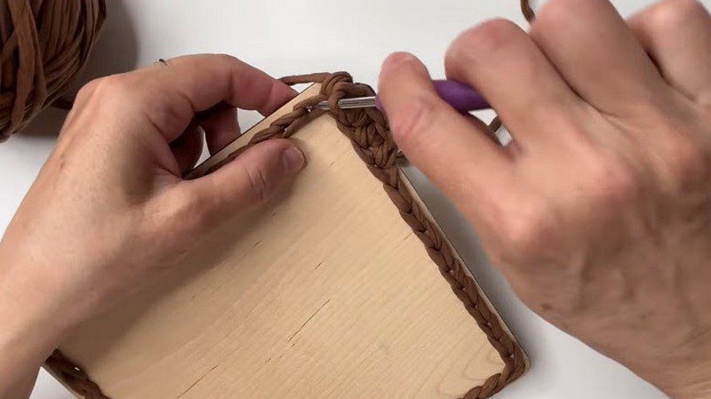 First round of brown stitches worked around the wooden base edge.