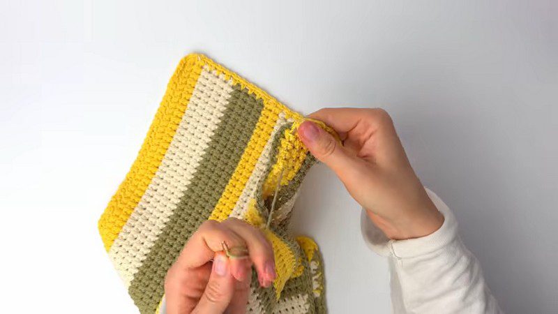 Folded striped piece being sewn together along the side edge.