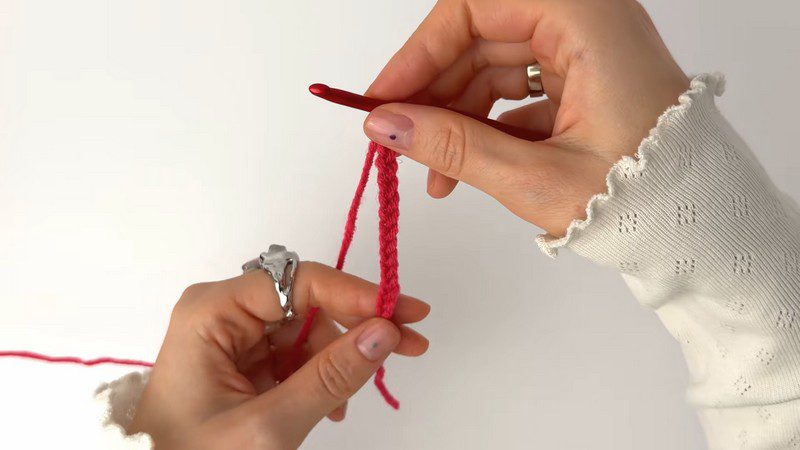 Red yarn starting chain held beside the hook.