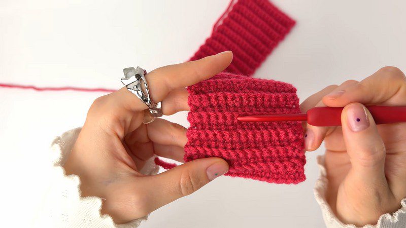 Ribbed red fabric growing row by row on the hook.