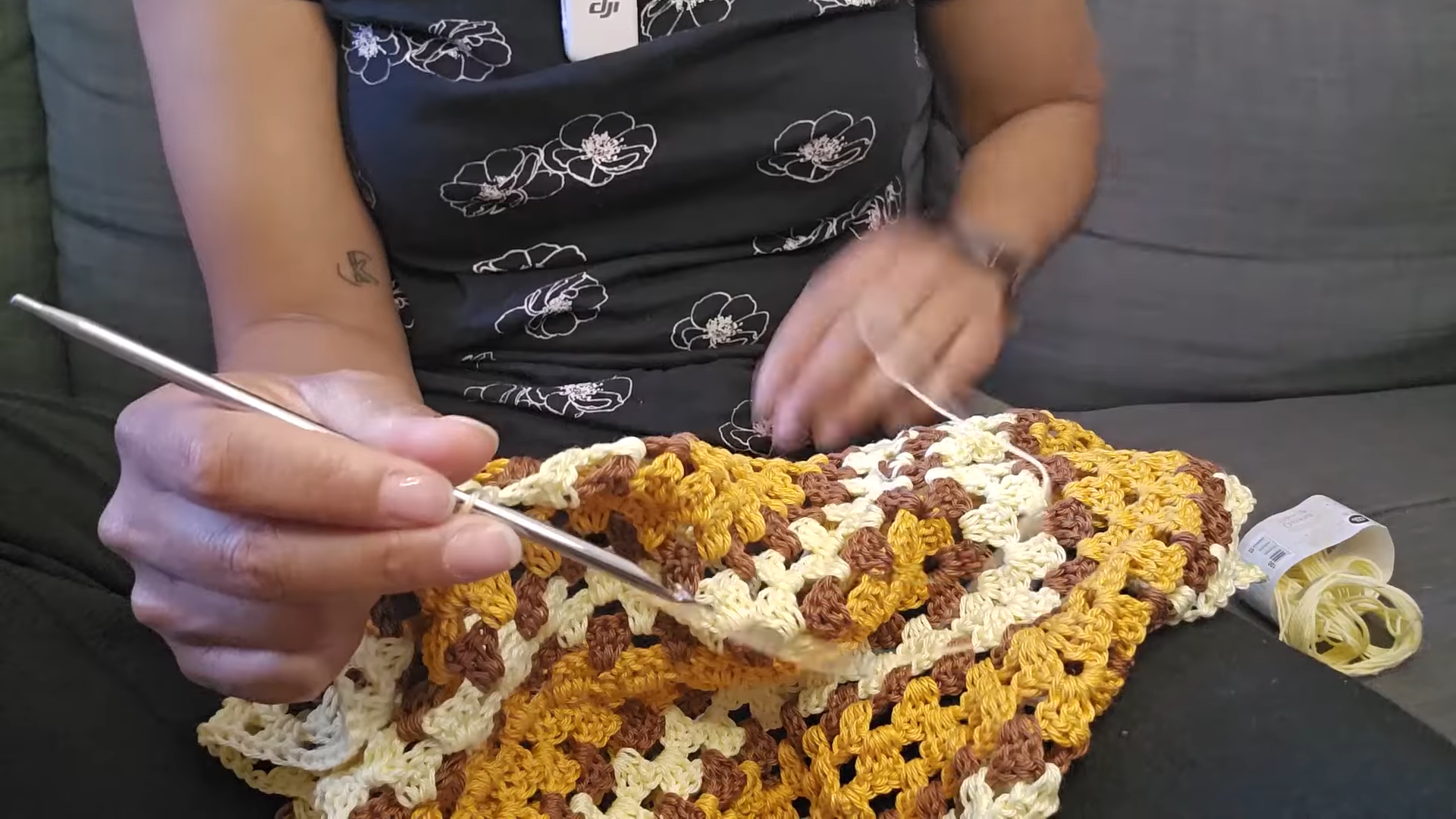 Silver hook moving across the granny rows beside cream yarn.
