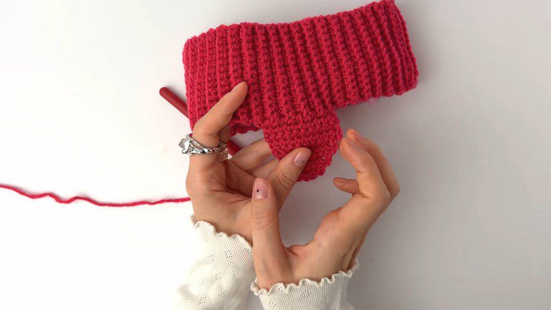 Small ear flap attached to the ribbed red crochet cap band.