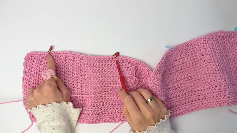 Stitch markers placed along the pink panel for joining.
