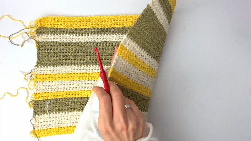 Striped crochet placemat panel in yellow, olive, and cream laid flat.